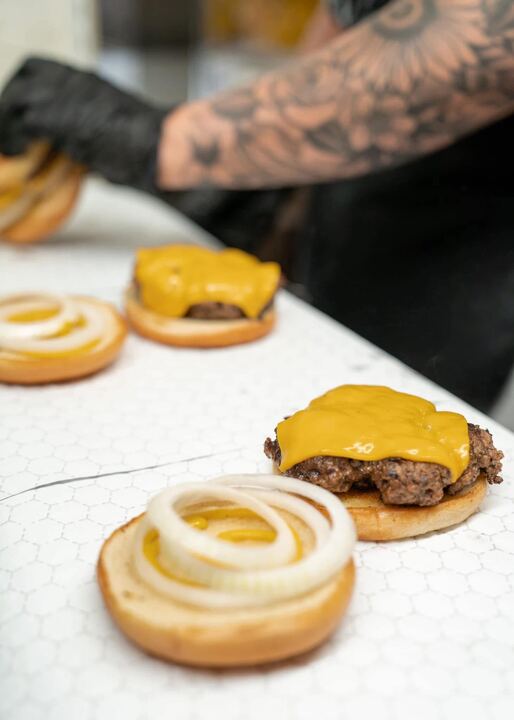 Cheeseburgers being built on toasted buns