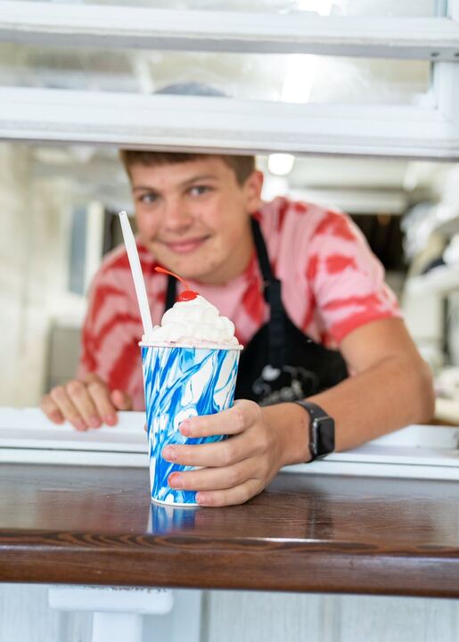 A crew member at the window with a blended treat in a blue cup