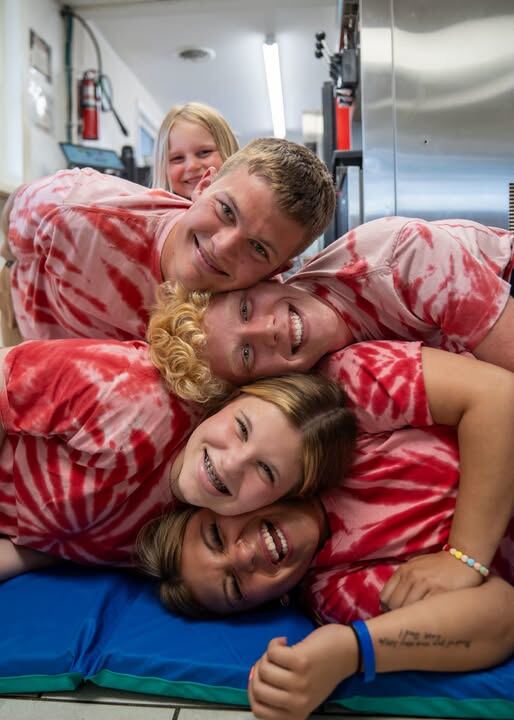 The crew piled up laughing in their red tie-dye shirts