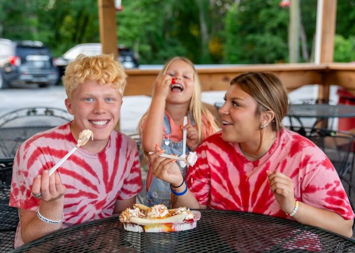 Three friends in red tie-dye sharing Ice Cream Nachos on the patio